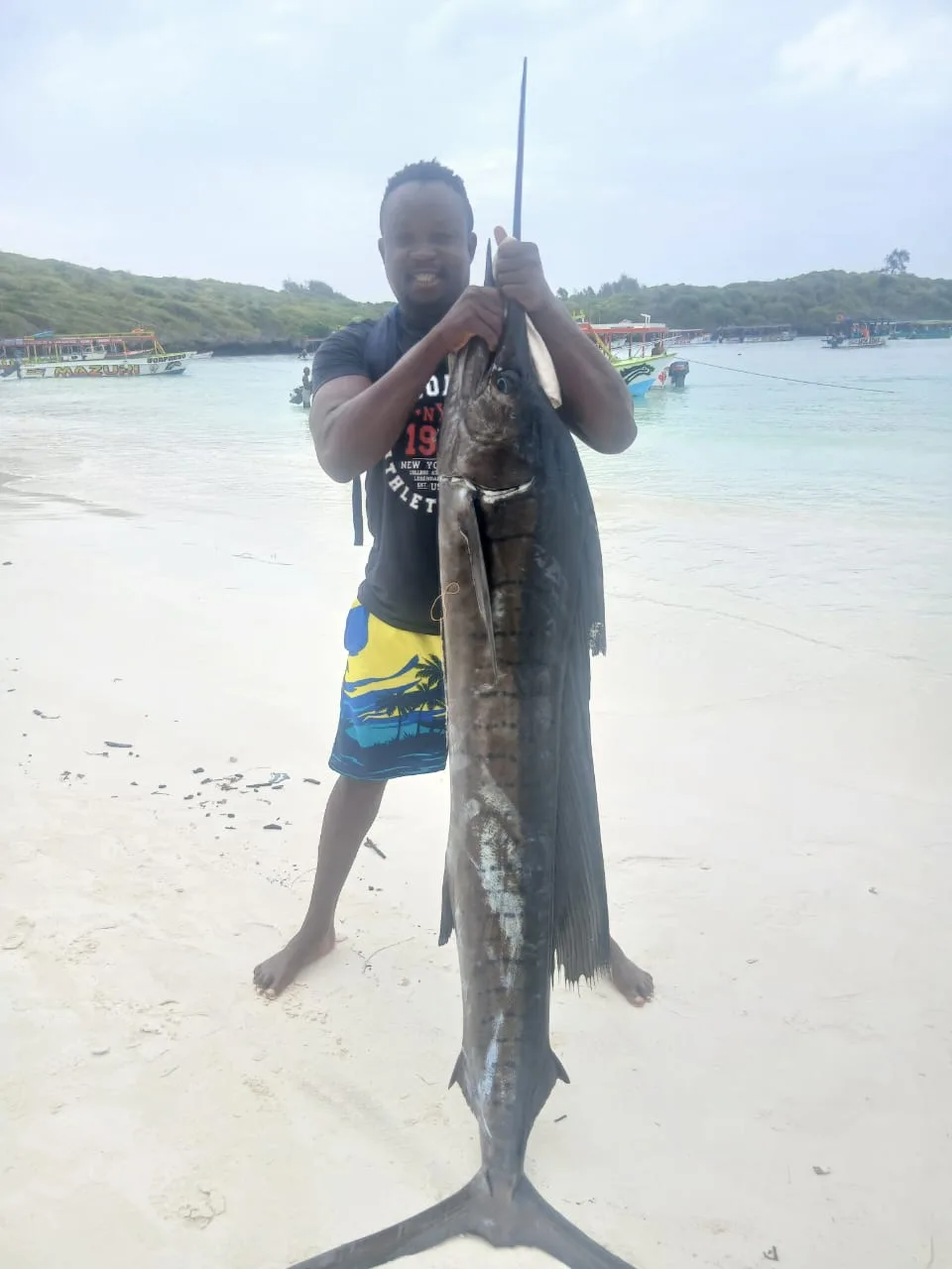 Pescatore con un grande pesce sulla spiaggia